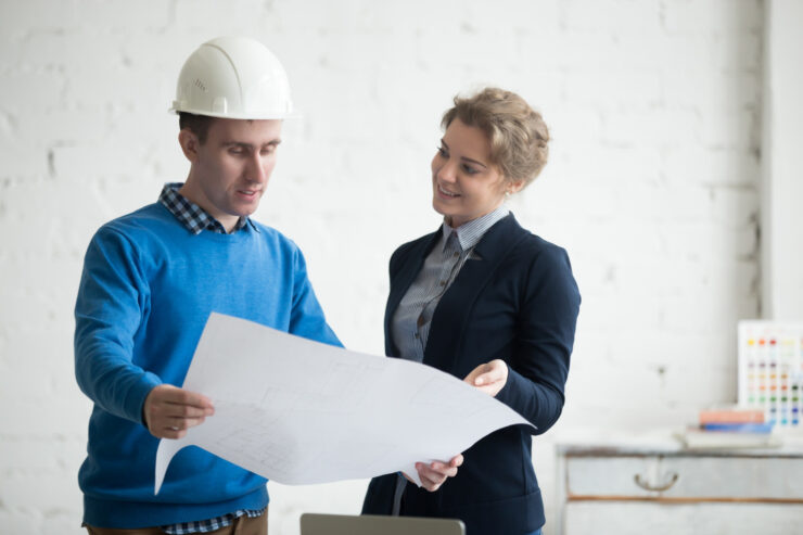 A contractor and investor discussing renovation plans and costs over blueprints