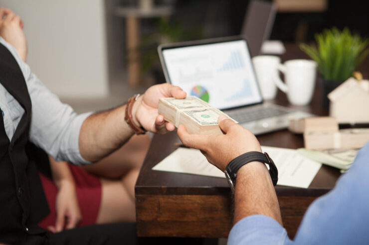 Private money loan transaction with cash exchanged across the table.