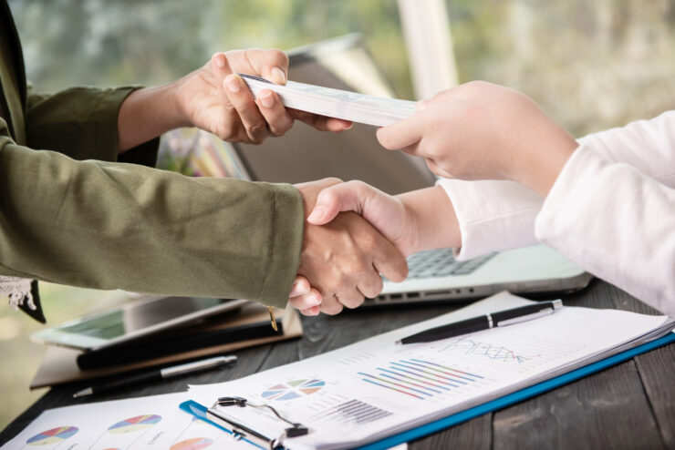 Private money loan agreement finalized with handshake and financial documents.