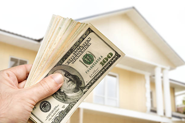 Hand holding cash for residential hard money loan with home view