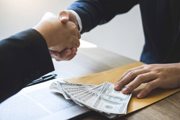 Commercial hard money lender closing a deal with cash and a handshake