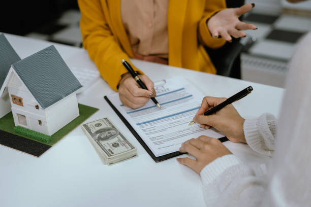 Land loan application signing with property model on desk