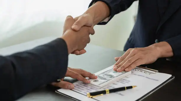 Private money loan agreement handshake with contract and cash